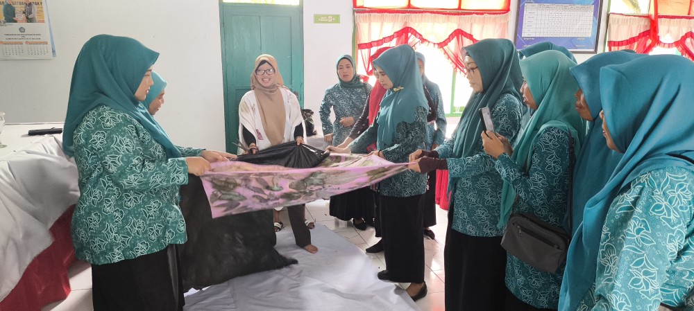 Gambar : Bersama-sama membuka kain yang telah dikukus bersama daun